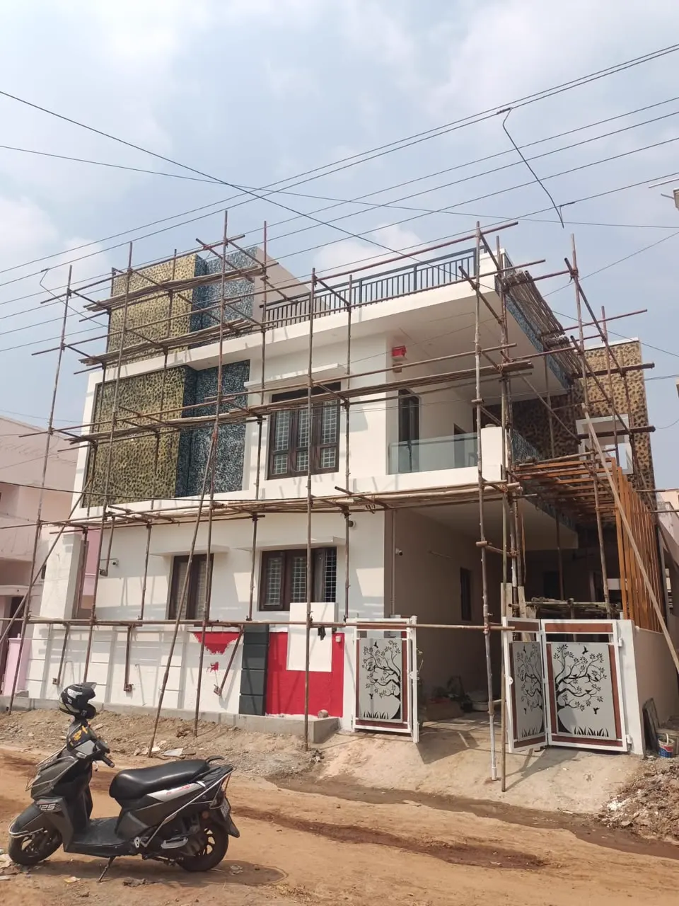 Three-storey residence with textured feature panels under scaffolding